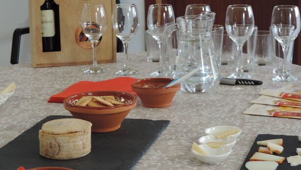 A dining table set with wine glasses, a wine bottle, cheese, and bread.