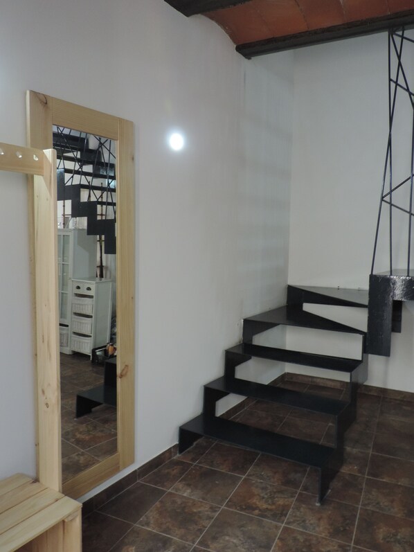 Un interior moderno con una escalera, una puerta de madera y un suelo de baldosas.