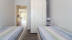Un dormitorio con dos camas, un armario y una pequeña zona de estar.