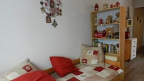 Una habitación pequeña y acogedora con una cama individual, una estantería y un atrapasueños en la pared.