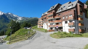 Un edificio de varios pisos con balcones, con montañas al fondo.
