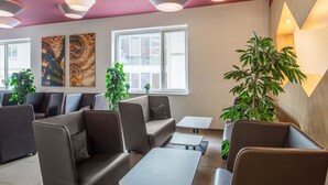 A modern waiting area with leather seating, a coffee table, and potted plants. - B&B Hotel Bayreuth (Bayreuth)