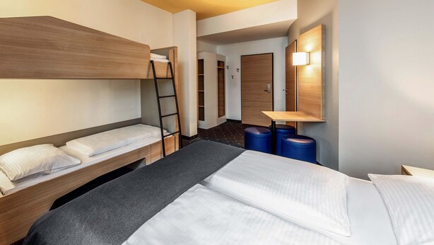 A hotel room with a bunk bed, a desk, a chair, a ladder, and a small table. - B&B Hotel Bayreuth (Bayreuth)