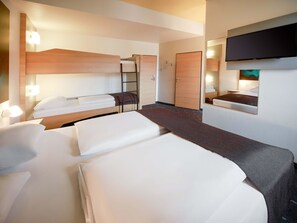 Una habitación de hotel moderna con dos camas, un televisor, un espejo y un escritorio pequeño.