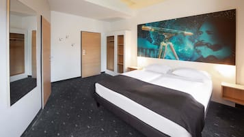 Una habitación de hotel con una cama grande, una mesita de noche, un armario y un cuadro colgado en la pared.