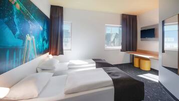 Habitación de hotel con una cama grande, un escritorio, un televisor de pantalla plana y un mural en la pared.