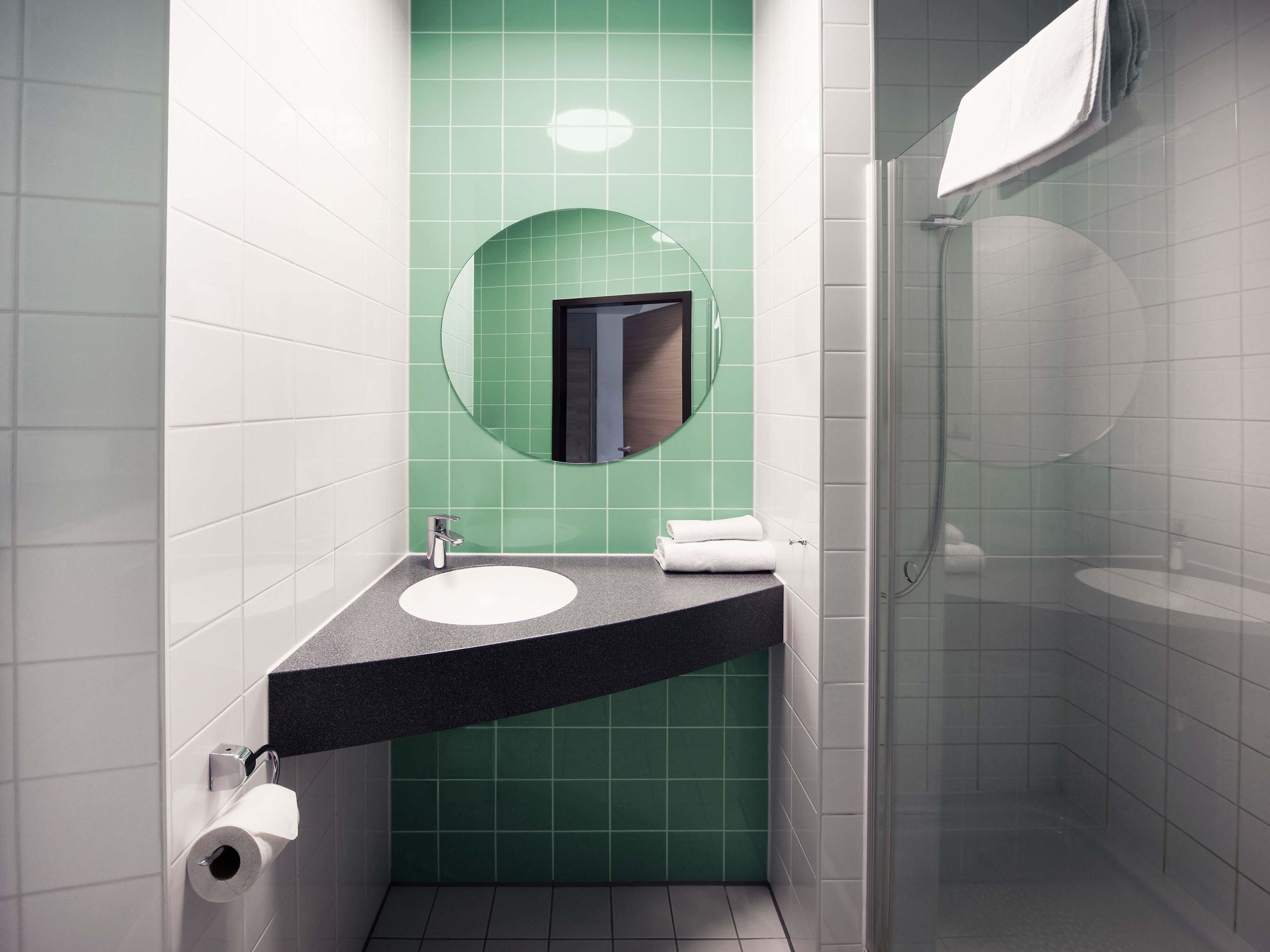 Ein modernes Badezimmer mit Waschbecken, Spiegel und einer Duschkabine aus Glas.