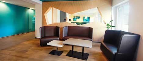 Un área de espera moderna con sofás de cuero, una mesa de centro y un mostrador de recepción de madera.