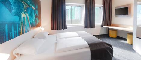 A hotel room with a large bed, a desk, a flat-screen TV, and a painting on the wall.