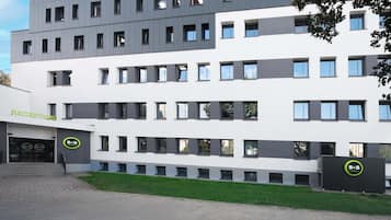 Un hotel moderno con área de recepción, varios pisos y un césped verde al frente.