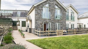 A two-story house with a stone facade, large windows, and a wooden deck. - Chi An Treth - sleeps 6 guests  in 3 bedrooms (Bude)