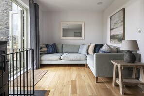 Ein modernes Wohnzimmer mit einem grauen Sofa, einem Holztisch und einem Bild an der Wand.