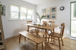 A dining area with a wooden table and chairs, a bench, and a window with blinds.