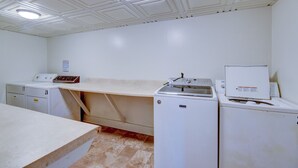 Een wasserette met een grote tafel, twee wasmachines en een droger.
