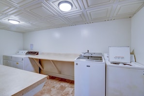 Un cuarto de lavandería con una mesa grande, dos lavadoras y una secadora.