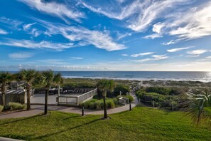 Una propiedad costera con terraza con vista a la playa, un patio cercado y un camino que conduce a la playa.