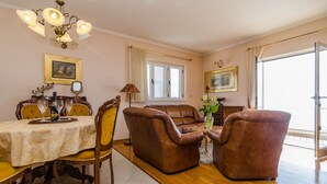 A dining area with a table set for four, a brown leather sofa, and a chandelier.