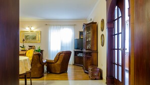 A living room with a dining area, a television, and a large wooden door.