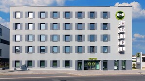 Un moderno edificio de hotel con recepción, varias ventanas y un cartel de estacionamiento.