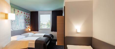 A hotel room with two beds, a small desk, a chair, and a window with curtains.