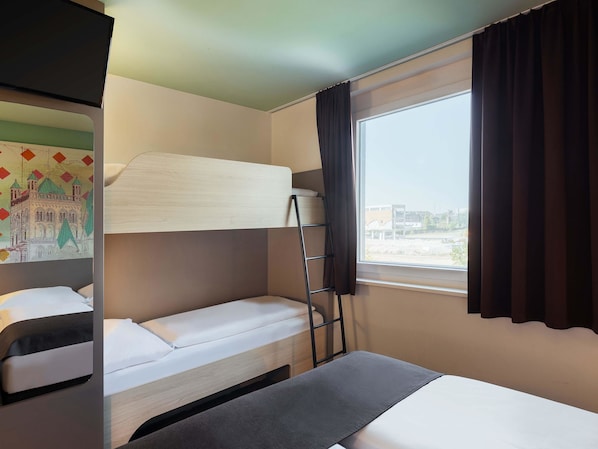 Habitación de hotel con literas, una cama individual, una ventana con cortinas, un televisor montado en la pared y un cuadro.