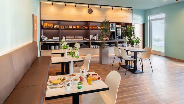 Un comedor moderno con mesas, sillas y un bufé al fondo.