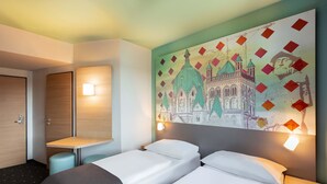 Una habitación de hotel con dos camas, un escritorio y una obra de arte colgada en la pared.