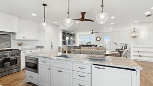 A spacious kitchen with white cabinetry, a large island, stainless steel appliances, and pendant lighting. - The Pelican`s Nest Egg - Hosted By Moore AI Rentals (Fernandina Beach)