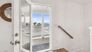 A room with a white door leading to a balcony with a view of houses and palm trees. - The Pelican`s Nest Egg - Hosted By Moore AI Rentals (Fernandina Beach)