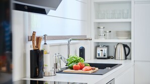 A modern kitchen with a black countertop, a sink, and a cutting board with vegetables. - Villa Cali (Oprtalj)
