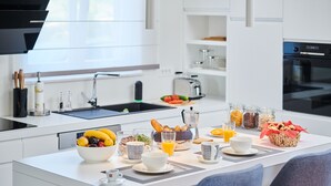 A modern kitchen with a central island, equipped with a sink, a coffee maker, and various breakfast items. - Villa Cali (Oprtalj)