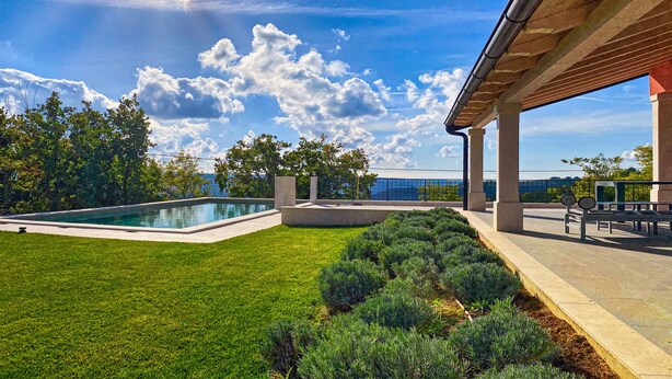 A modern outdoor pool area with a clear sky and a view of the sea. - Villa Cali (Oprtalj)