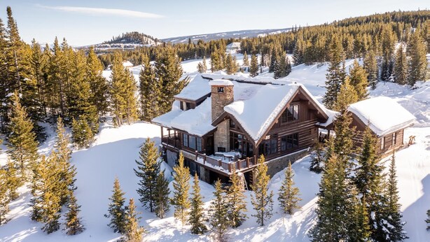 A log cabin with a stone chimney, surrounded by snow-covered trees and a clear sky. - Hot Tub| Ski-In/ Ski-Out | Sonos Sound (Big Sky)