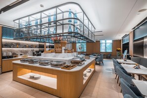 A modern hotel lobby with a central serving area, seating arrangements, and a glass display of decorative bottles. - Starway Hotel (Shanghai Anting Metro Station) (SHANGHAI)