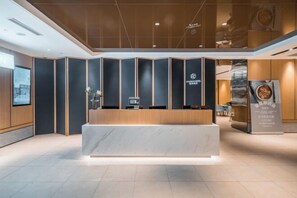 A modern reception area with a marble counter, dark paneling, and a logo on the wall. - Starway Hotel (Shanghai Anting Metro Station) (SHANGHAI)