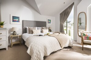A bedroom with a large bed, bedside tables, a mirror, and artwork on the walls. - Chi An Mor - sleeps 6 guests  in 3 bedrooms (Bude)