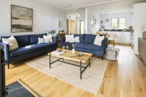 A modern living room with two sofas, a coffee table, and a kitchen in the background. - Chi An Mor - sleeps 6 guests  in 3 bedrooms (Bude)