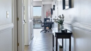 A hallway with a tiled floor, a desk with a plant, and a door leading to a balcony. - DT~ Free parking~ Sunset river views~ WiFi~ W/D (Wilmington)