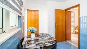 A hallway with a round table, a vase with flowers, and wooden doors leading to other rooms. - Apartment & Rooms Alan (Dubrovnik)