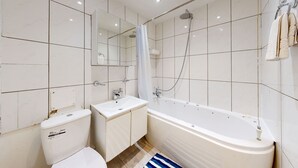 A modern bathroom with a toilet, sink, and bathtub. - Amazing 2 Bed House w/ Private Parking & Private Garden (London)