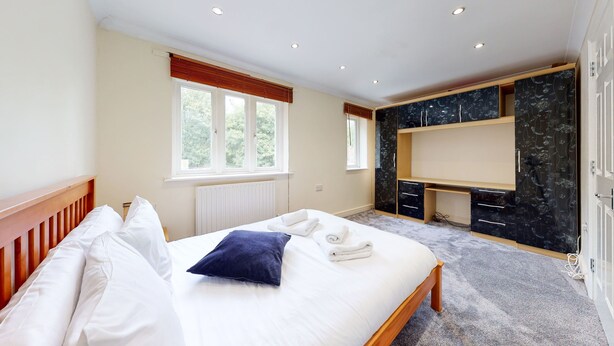 A bedroom with a bed, a window, a built-in desk, and a wardrobe. - Amazing 2 Bed House w/ Private Parking & Private Garden (London)