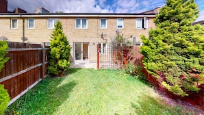 A two-story brick house with a fenced backyard, a wooden fence, and a variety of trees. - Amazing 2 Bed House w/ Private Parking & Private Garden (London)