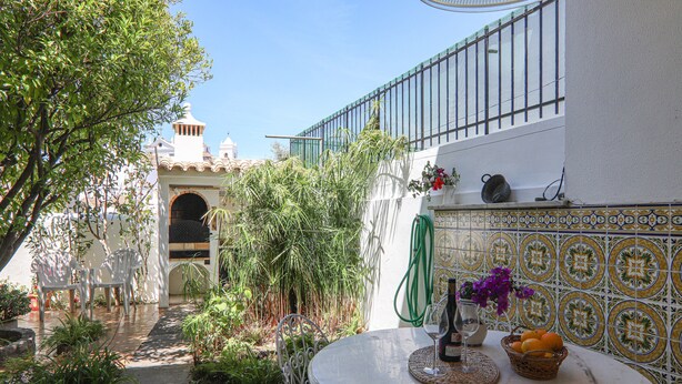 Une terrasse avec une table ronde, des chaises et une vue sur un bâtiment dont le mur est recouvert de carreaux.