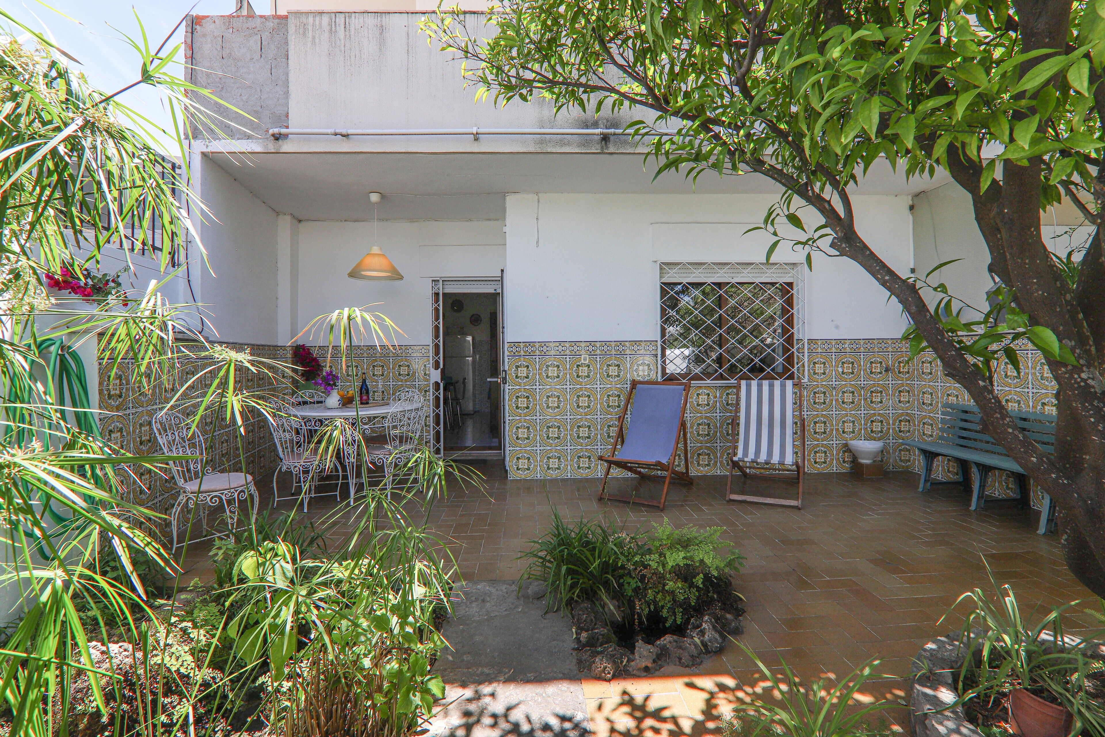 Un patio con una mesa y sillas, un banco y plantas en macetas.