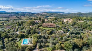 An aerial view of a countryside property with a large house surrounded by trees, a swimming pool, and a view of distant hills. - Villa Il Foramasso 10+2, Emma Villas (Lucciana)