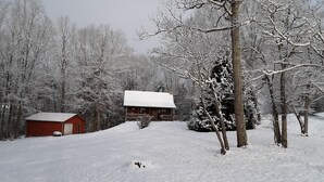 A snow-covered landscape with a cabin and a red shed.