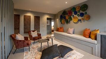 A modern living room with a sofa, two armchairs, a coffee table, and a patterned rug.