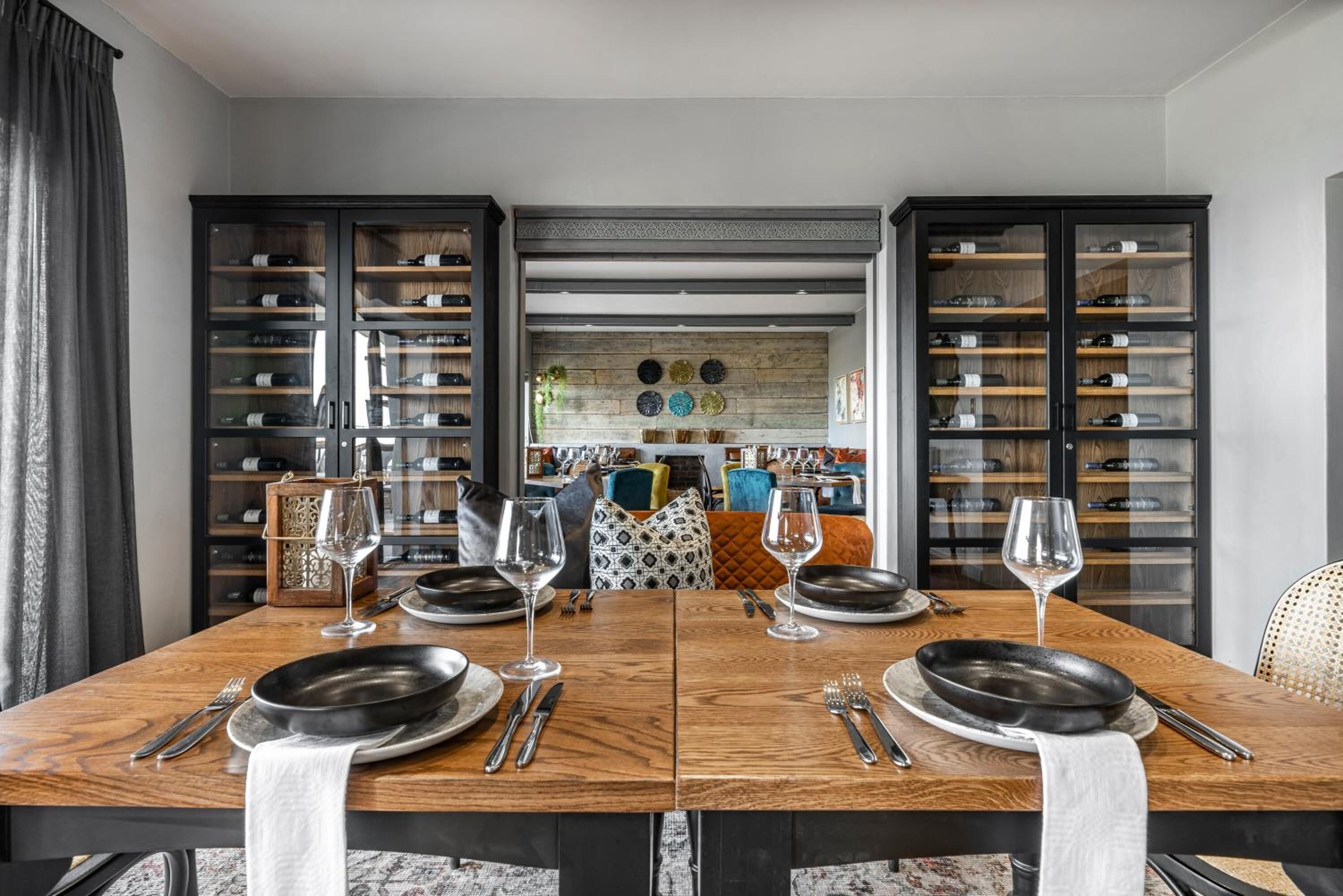 Un coin repas avec une table en bois dressée pour quatre personnes, bordée de meubles-bar à vin.
