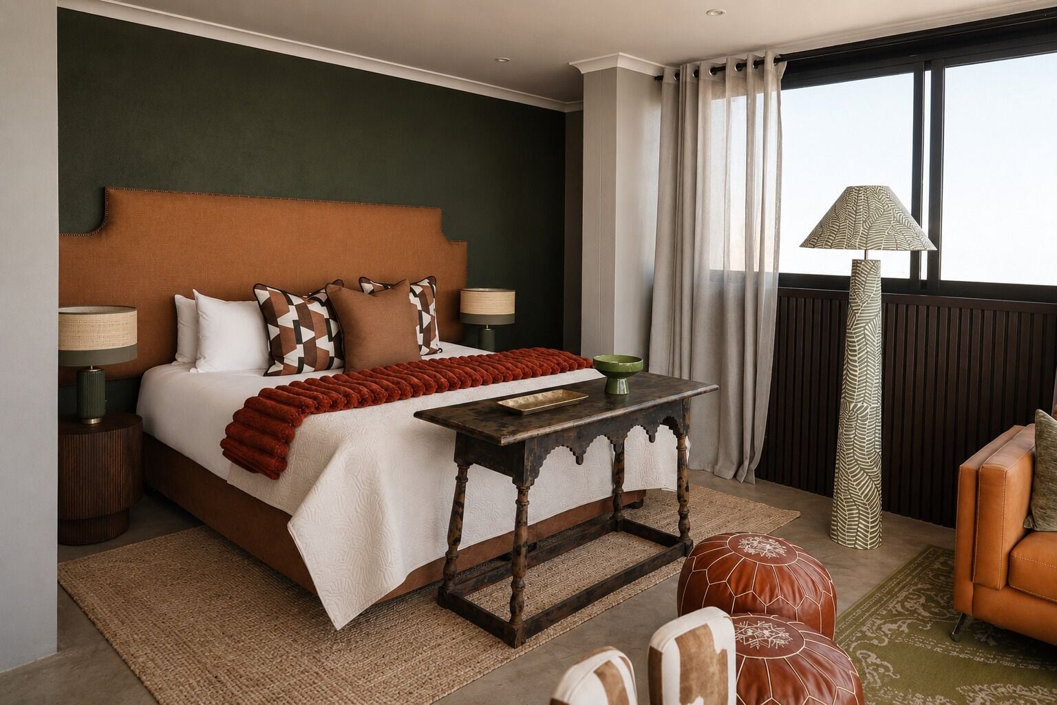 Une chambre d’hôtel avec un grand lit, deux tables de chevet, une petite table, un canapé et une vue sur l’extérieur.
