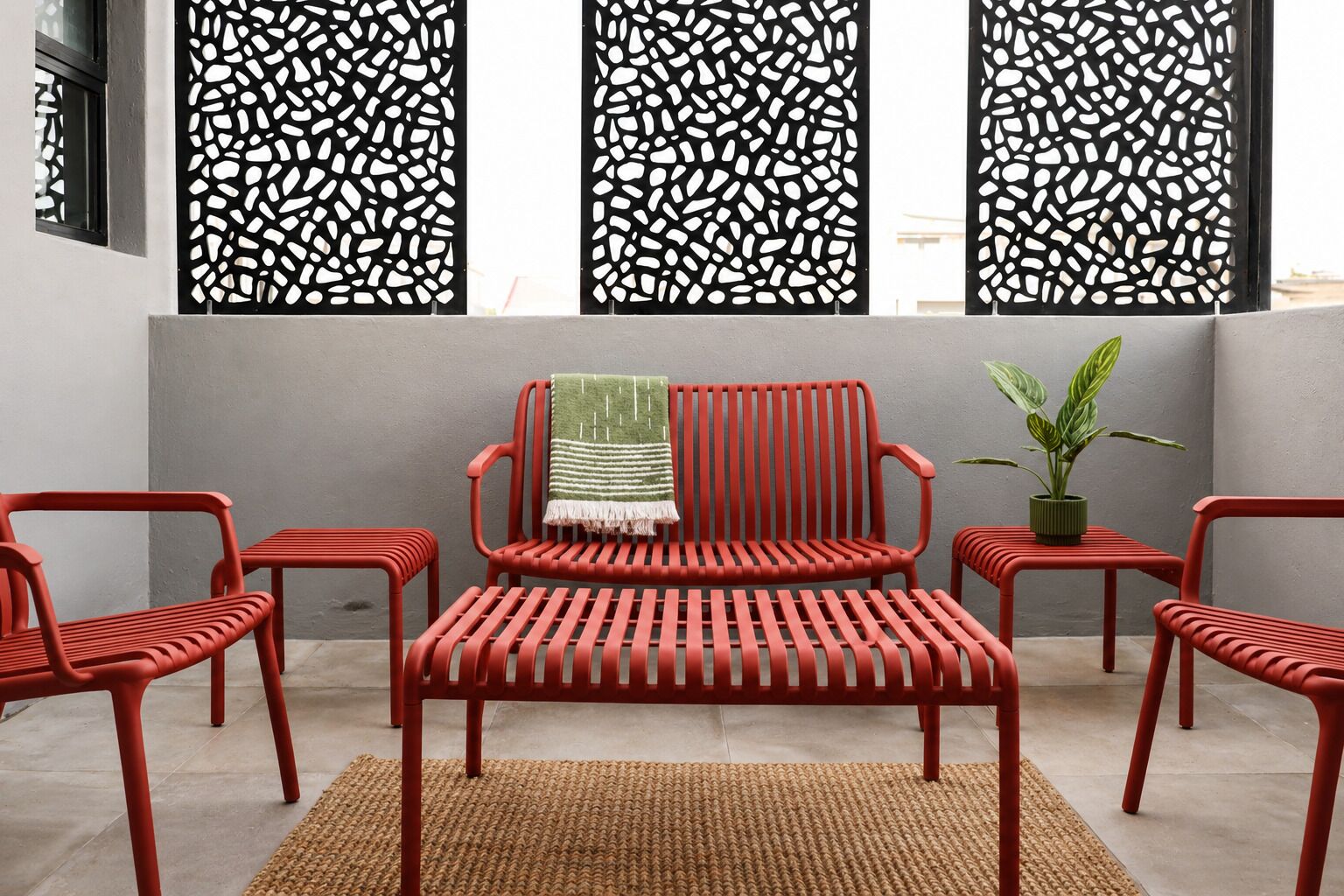 Une pièce avec une chaise rouge, un banc et une petite table, sur laquelle se trouve une plante.